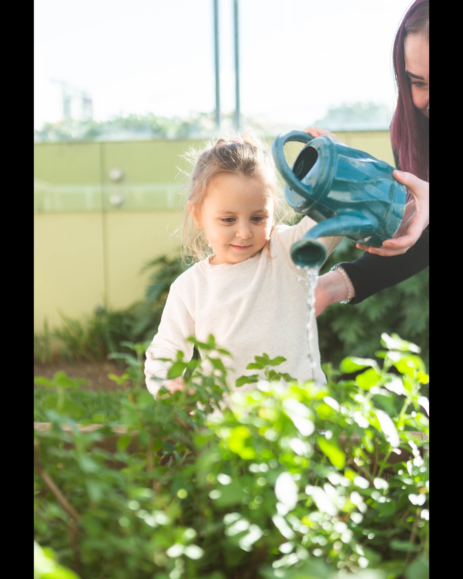 A child tending the garden with an educator at Strathfield Early Learning